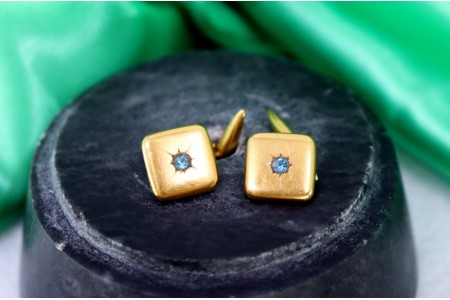 Botões de punho em ouro de formato quadrados e côncavos com zircónia azulada.